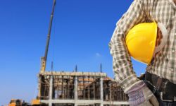 Worker and the blurred construction against blue sky